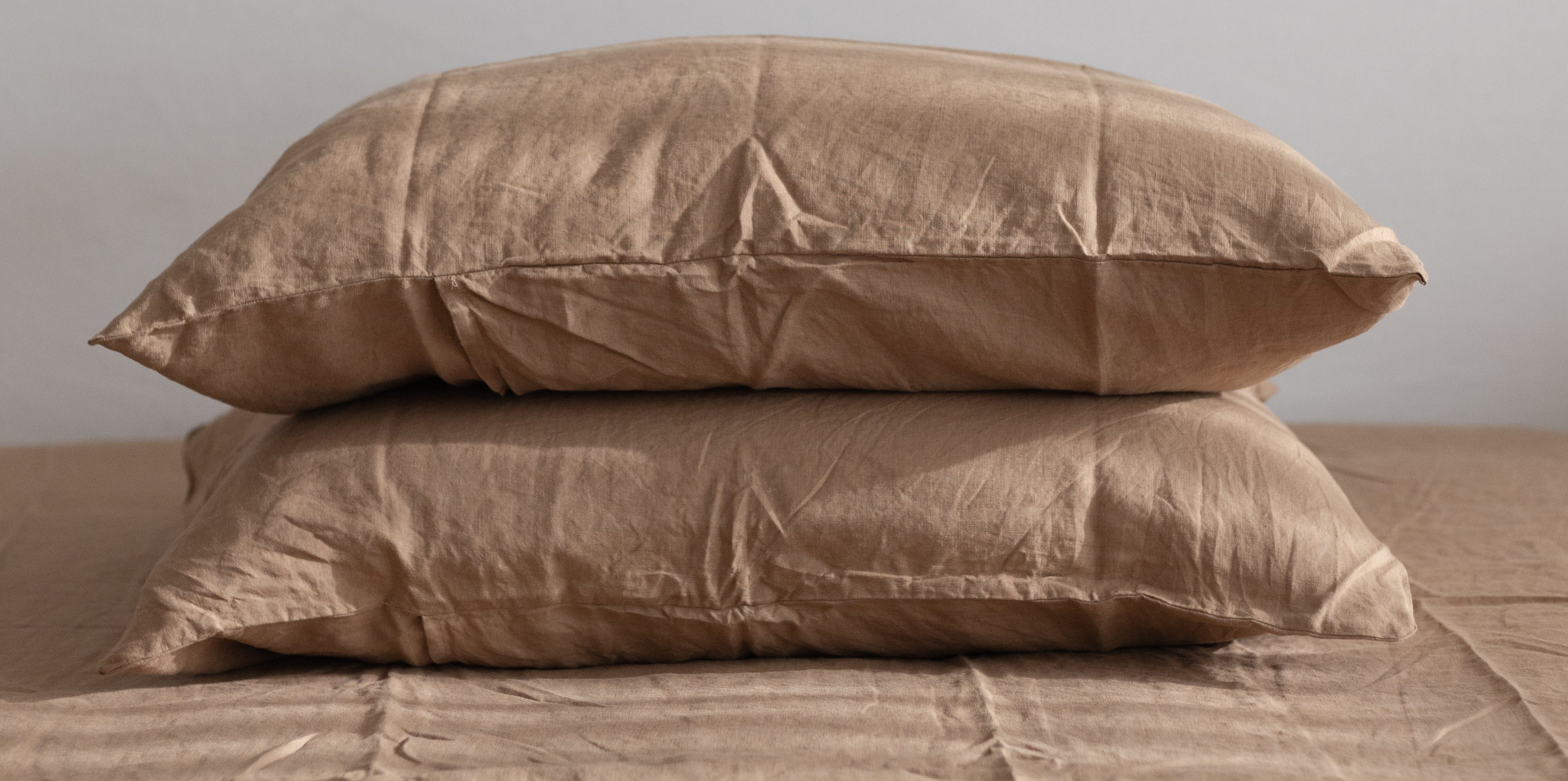Two brown linen pillows on a matching brown linen fitted sheet